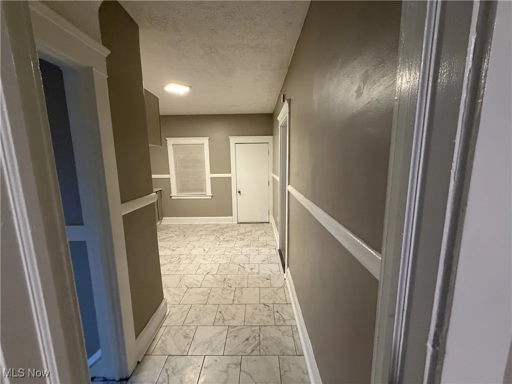 Hall with a textured ceiling and light marble finish floors