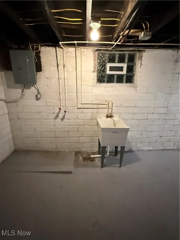 Unfinished basement with electric panel and a sink