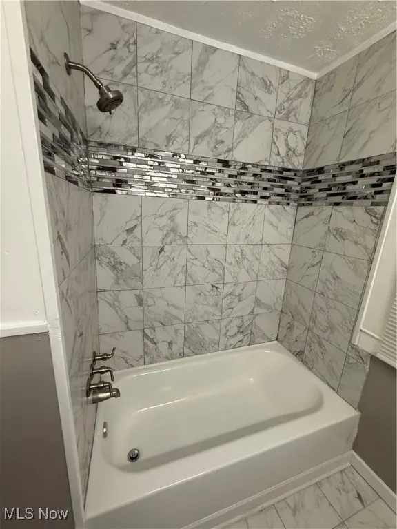 Full bathroom with marble finish floors and  shower combination