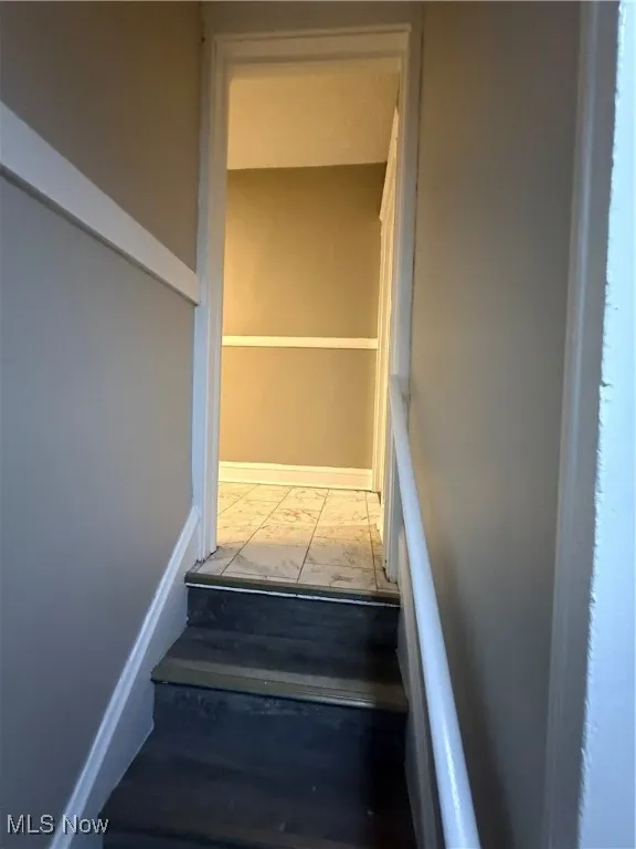 Staircase featuring marble finish flooring and baseboards