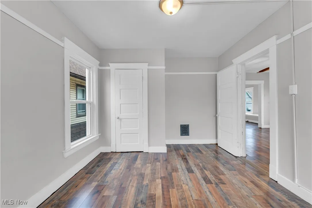 Empty room with dark wood-style flooring and baseboards