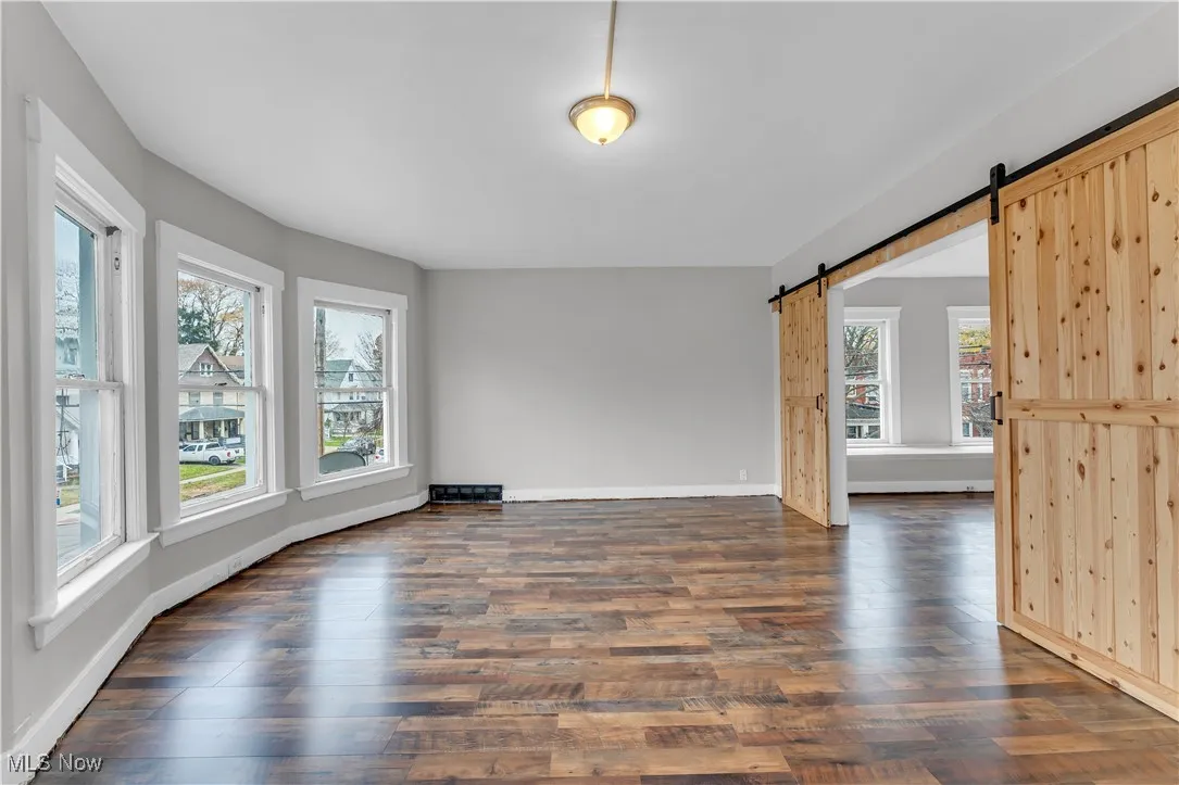 Unfurnished living room featuring dark wood-style flooring and a barn door
