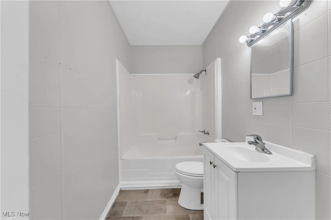Bathroom with tile walls,  shower combination, and vanity