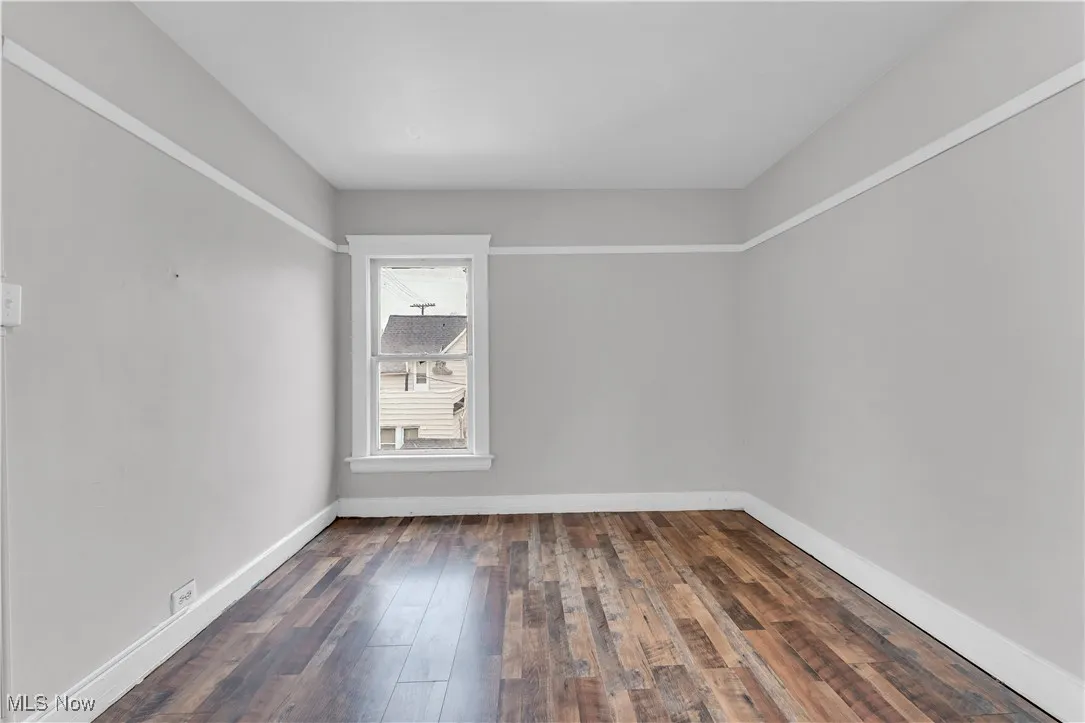 Spare room featuring dark wood-style floors and baseboards