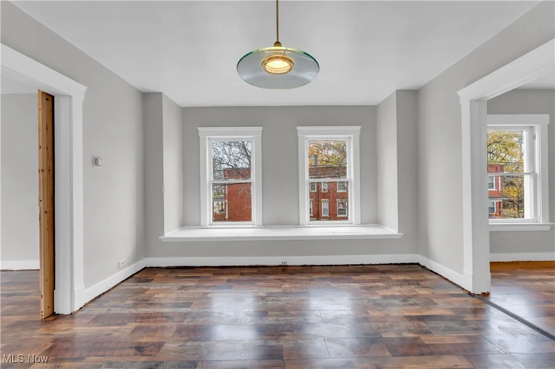 Unfurnished dining area with dark wood-style flooring and baseboards