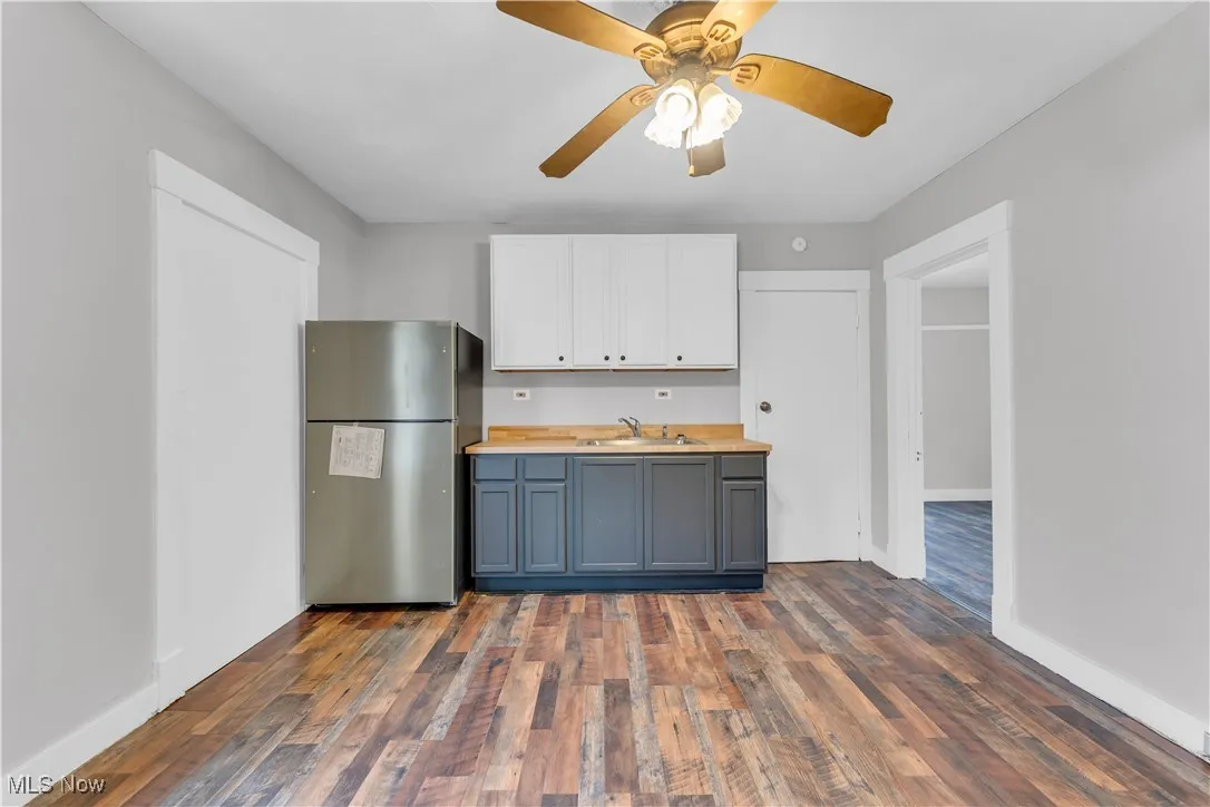 Kitchen with freestanding refrigerator, dark wood-style floors, white cabinets, a ceiling fan, and wood counters