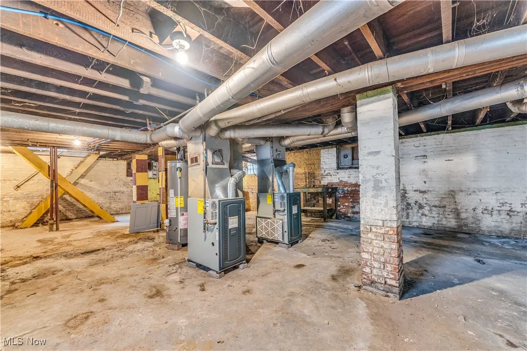 Unfinished below grade area featuring heating unit, water heater, and electric panel