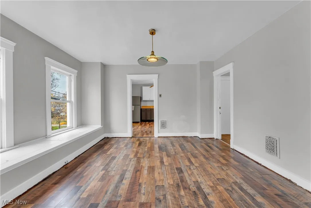 Empty room featuring dark wood-style flooring and baseboards