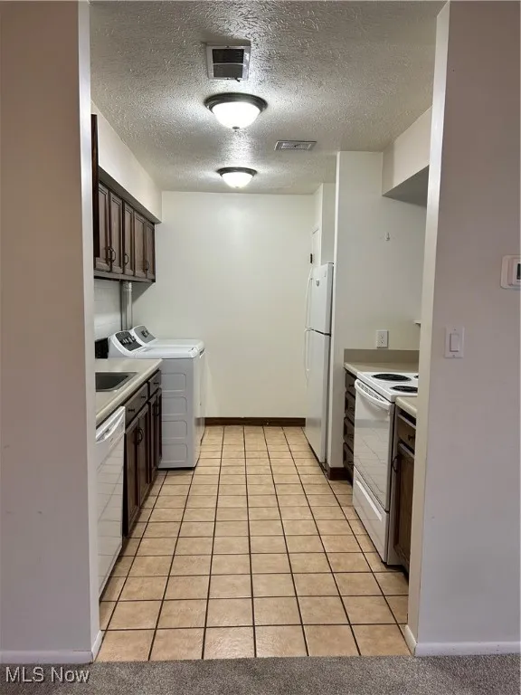 Kitchen featuring light tile patterned floors, dark brown cabinets, light countertops, and a textured ceiling