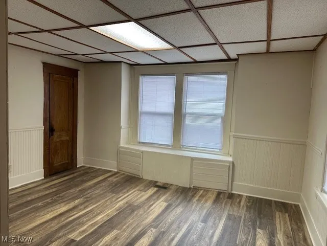 Unfurnished room with a wainscoted wall and dark wood-style flooring