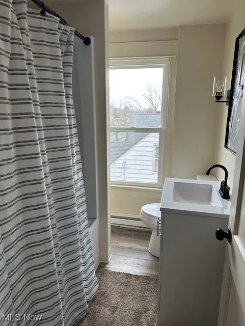 Full bathroom featuring vanity, baseboard heating, and shower / tub combo with curtain