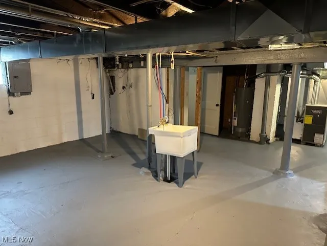 Unfinished basement featuring electric panel and water heater
