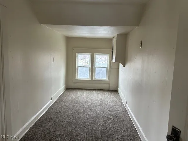 Carpeted spare room featuring baseboards
