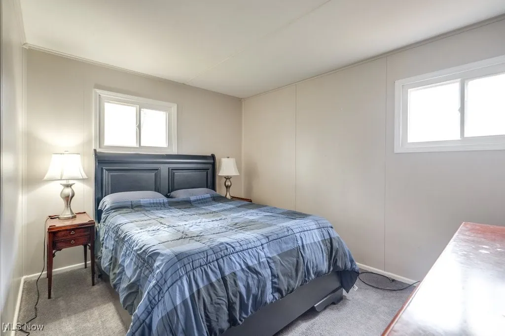 Bedroom featuring carpet floors, multiple windows, and a decorative wall