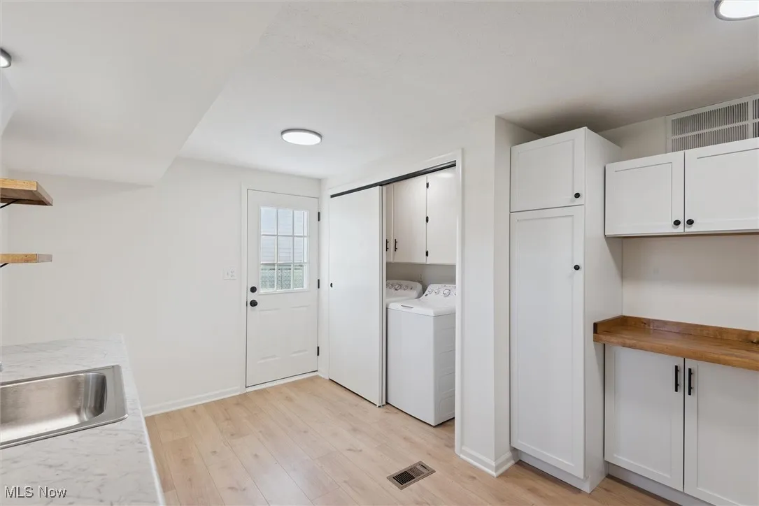 Laundry area featuring washer and dryer, light wood-type flooring, and cabinet space