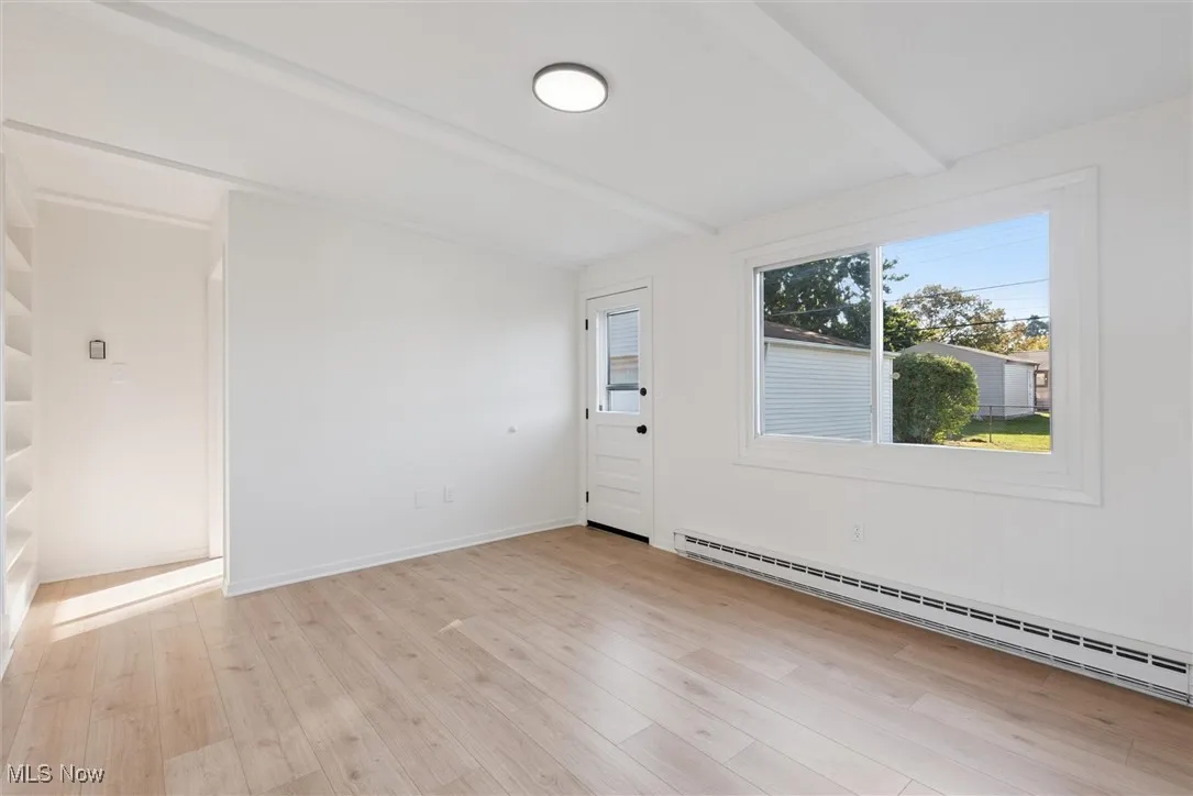 Empty room featuring a baseboard heating unit and light wood finished floors