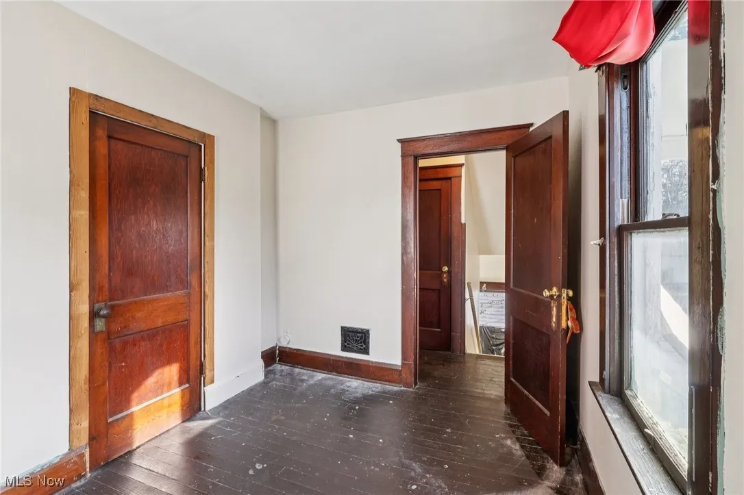 Empty room with healthy amount of natural light and dark wood-style floors