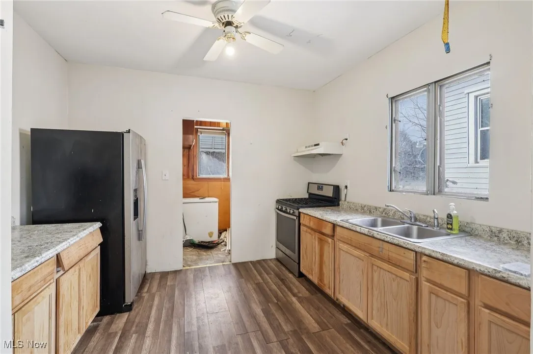 Kitchen with appliances with stainless steel finishes, light countertops, dark wood finished floors, ceiling fan, and under cabinet range hood