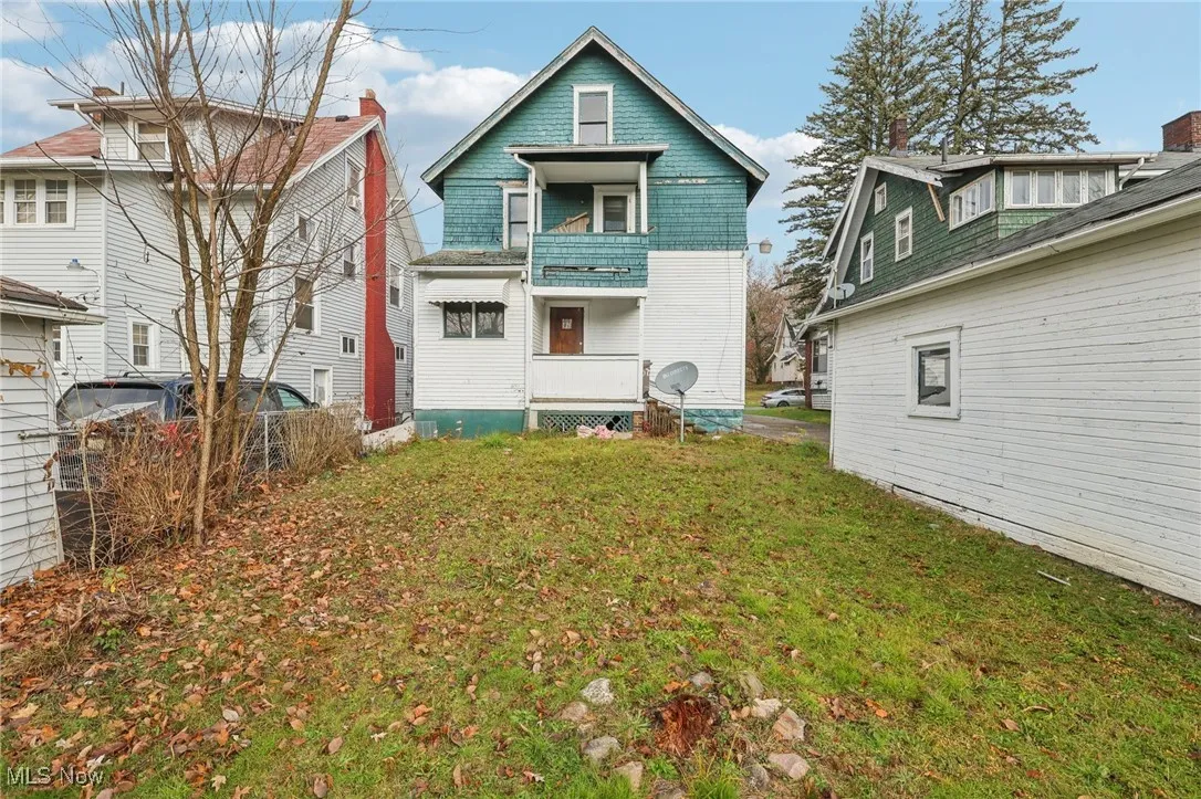 Back of property featuring a balcony and a lawn