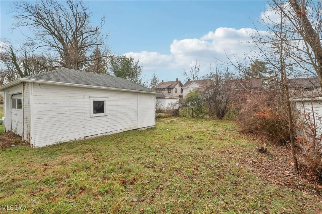 View of grassy yard featuring an outbuilding and a detached garage