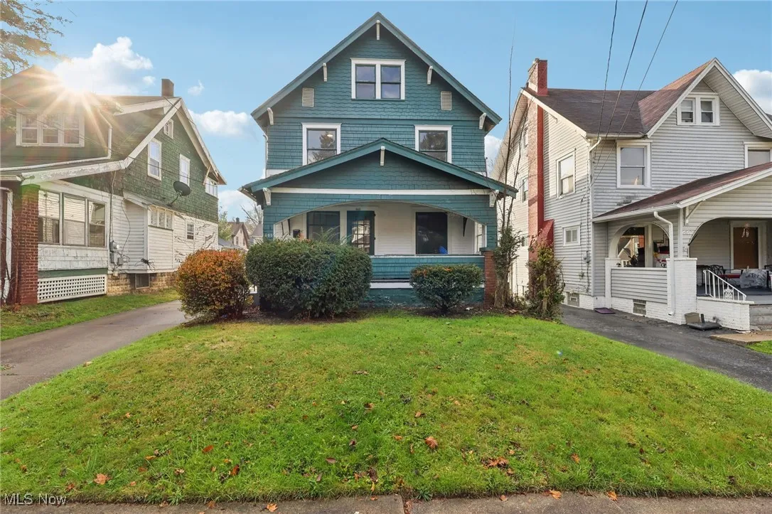 American foursquare style home featuring covered porch and a front yard