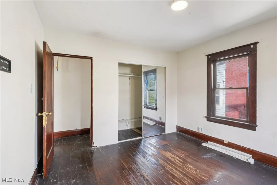 Unfurnished bedroom with dark wood-style flooring and a closet