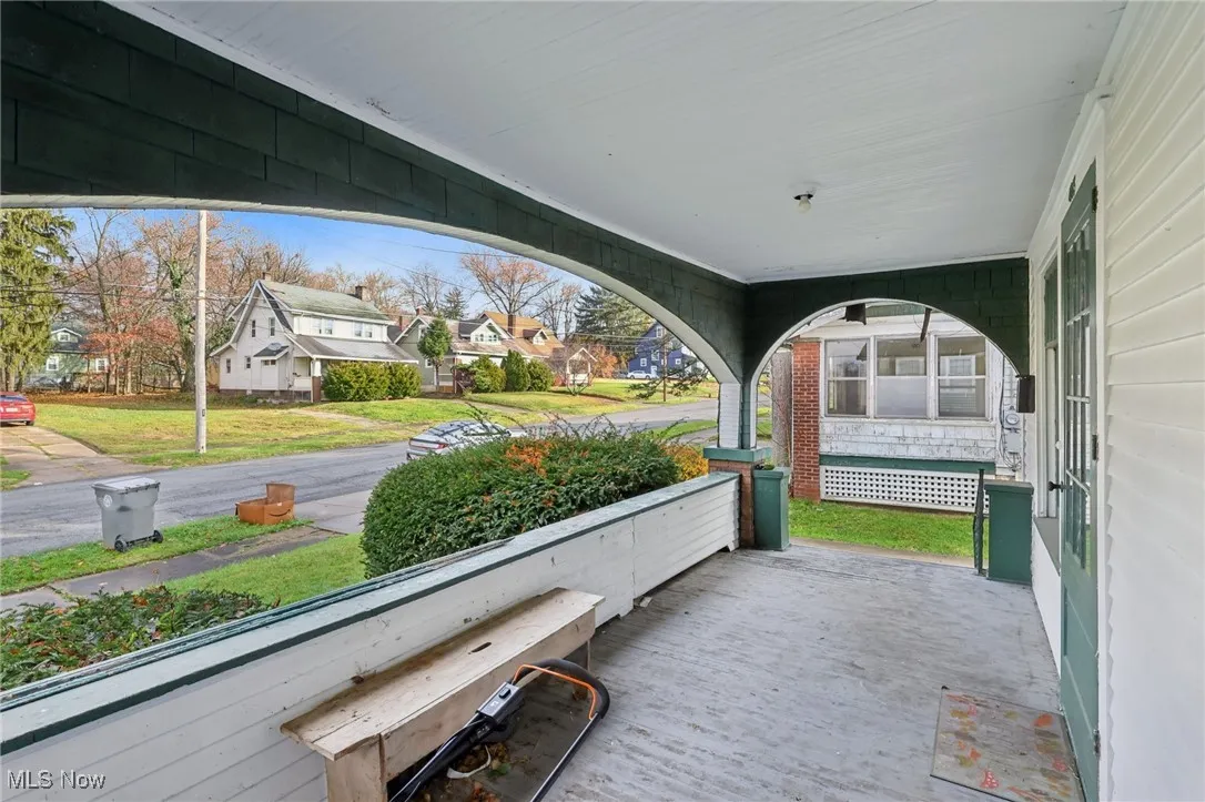 Covered porch with a residential view and a lawn