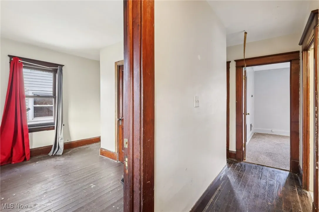 Hall featuring dark wood-style flooring and baseboards