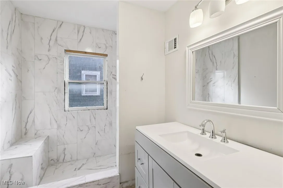 Bathroom with marble finish flooring, vanity, and a marble finish shower