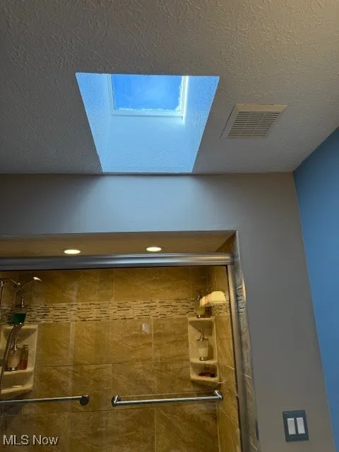 Bathroom view of a tile shower and a textured ceiling