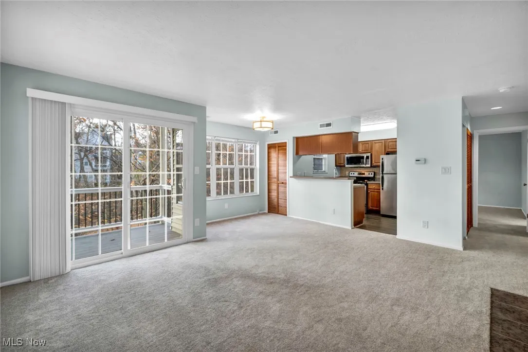 Unfurnished living room featuring dark colored carpet and baseboards