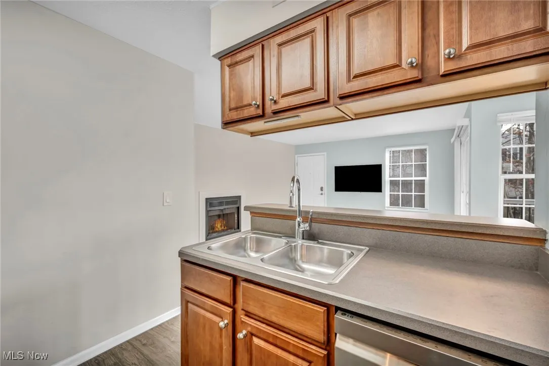 Kitchen with brown cabinets, stainless steel dishwasher, wood finished floors, and light countertops