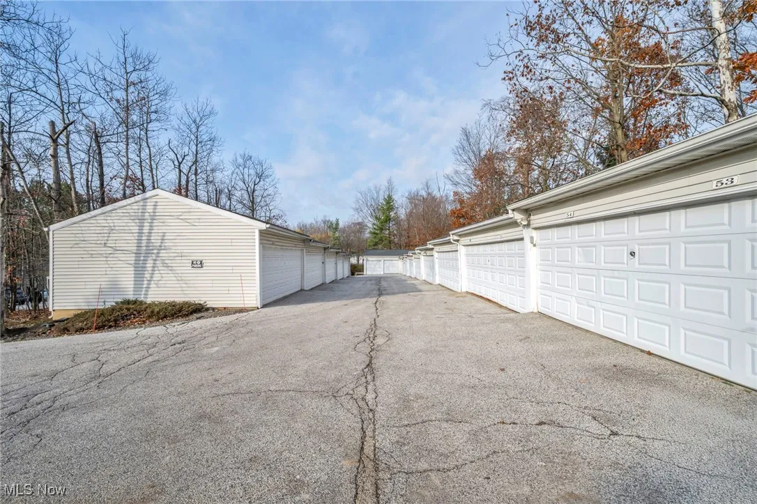 View of asphalt driveway featuring community garages