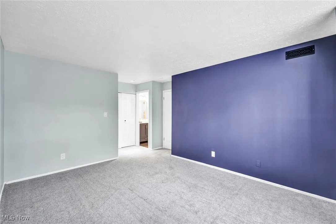 Carpeted spare room with a textured ceiling and baseboards