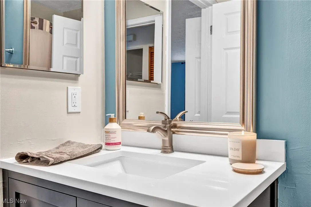 Bathroom with a textured wall and vanity