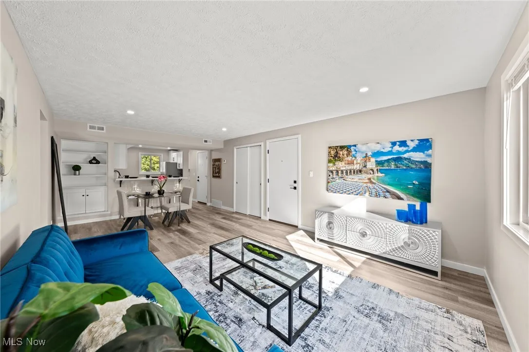 Living area featuring a textured ceiling, recessed lighting, and light wood-style floors