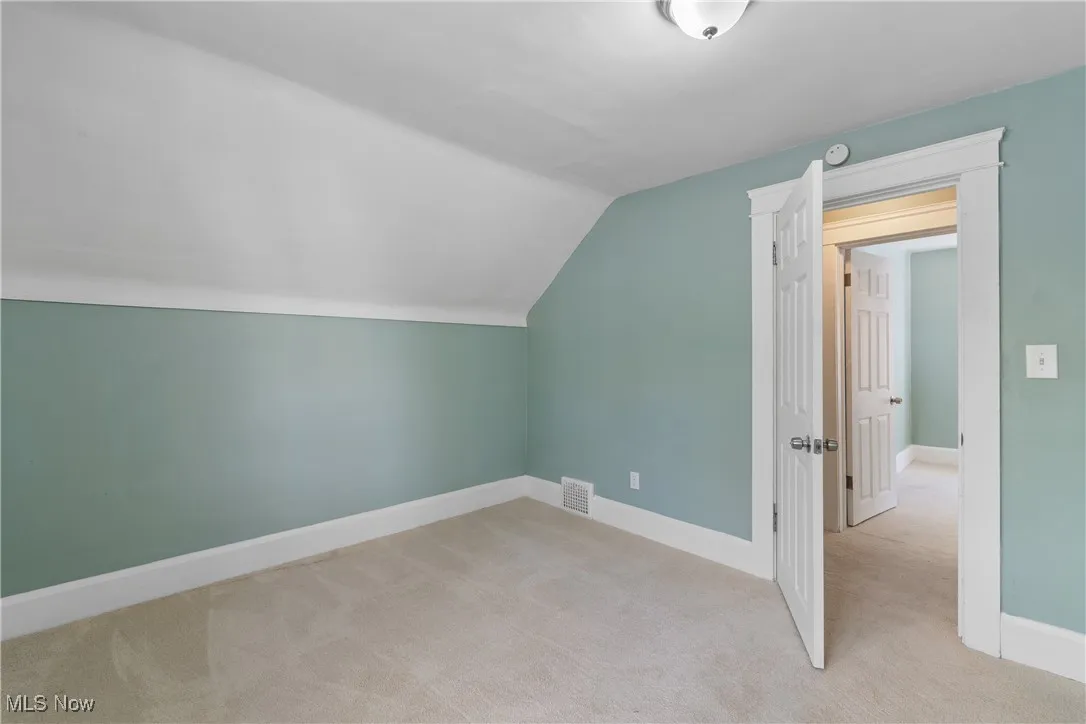 Bonus room with vaulted ceiling and light carpet