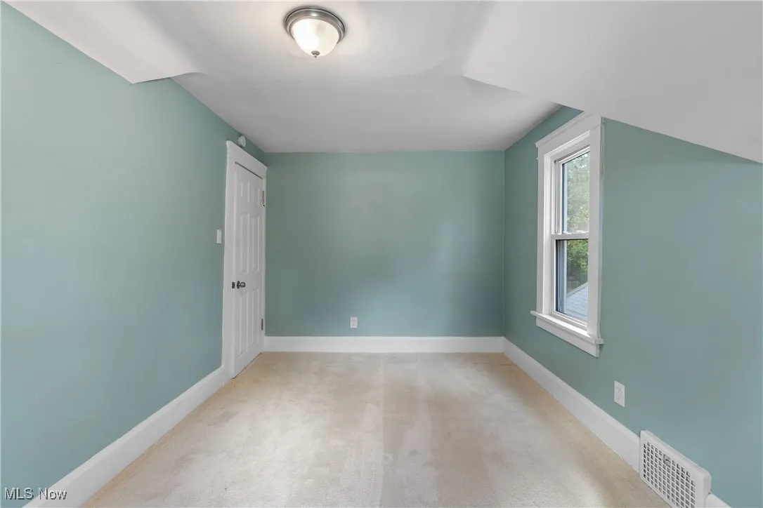 Additional living space with light colored carpet and baseboards