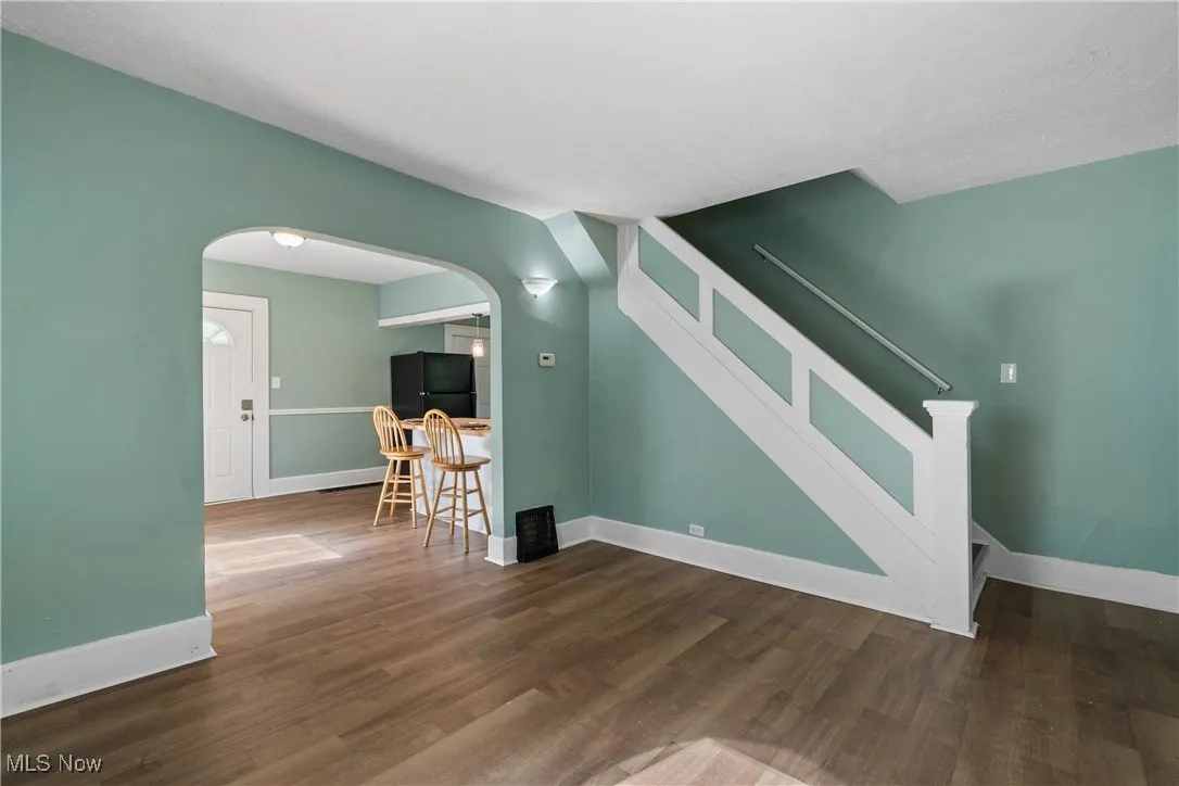 Unfurnished living room with dark wood-type flooring and arched walkways