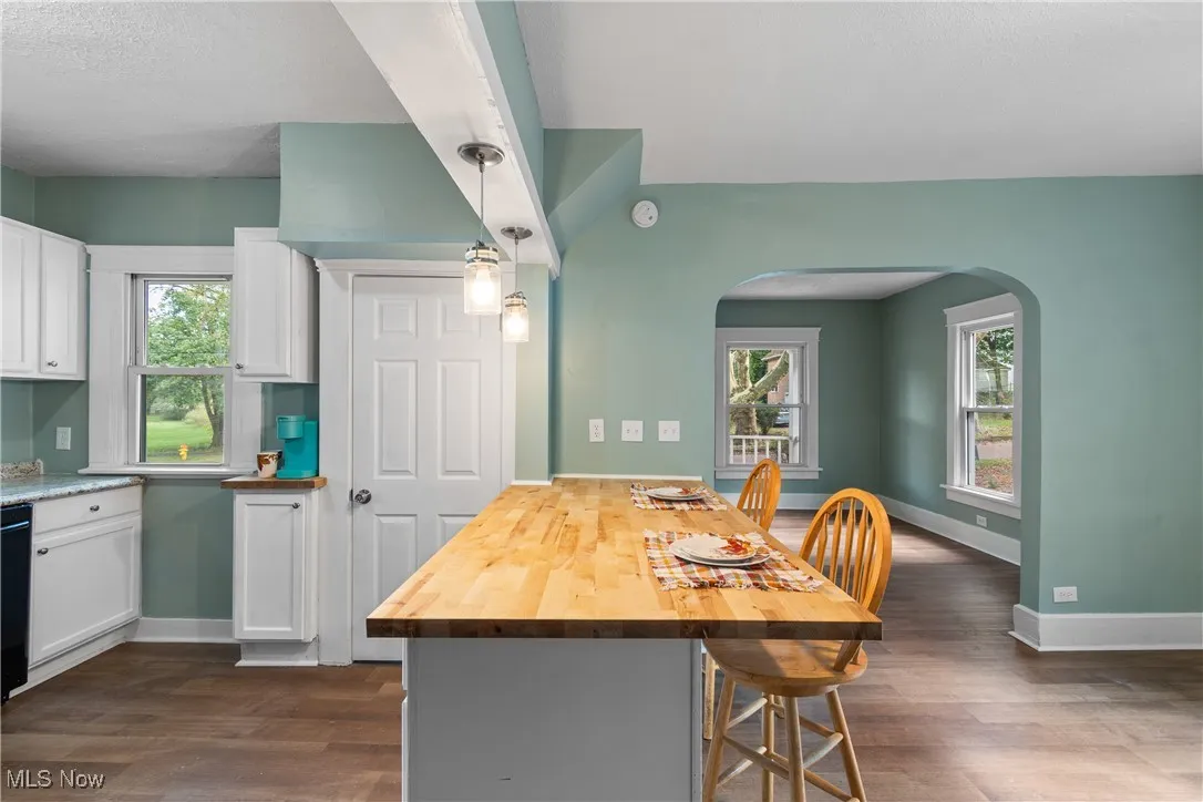 Kitchen with arched walkways, white cabinetry, plenty of natural light, and a textured ceiling