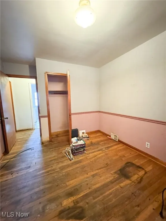 Unfurnished bedroom with hardwood / wood-style floors and a closet