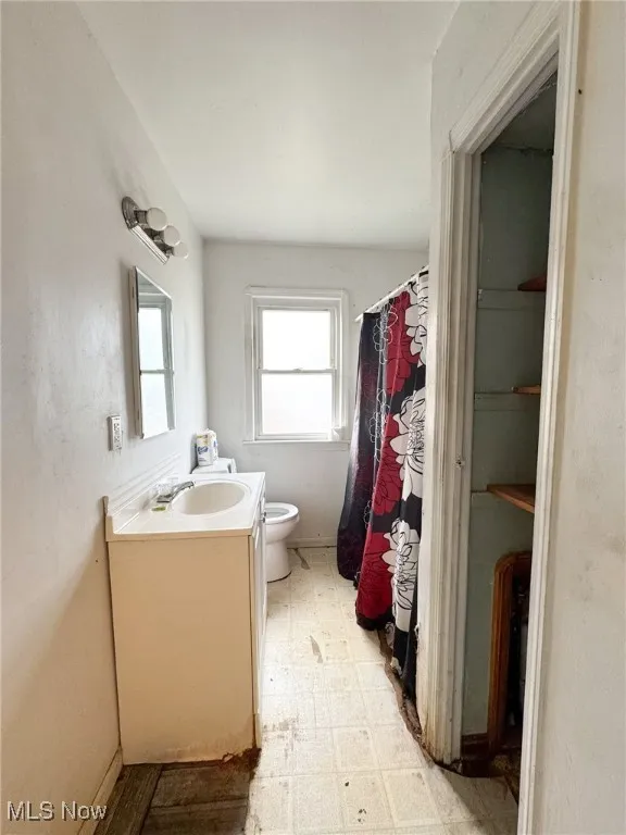 Bathroom featuring light flooring, curtained shower, and vanity