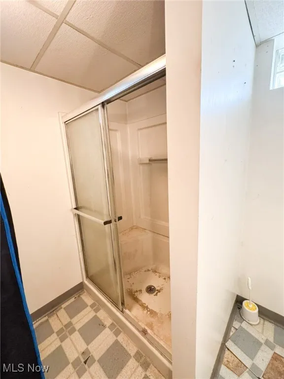 Bathroom featuring light floors and a shower stall