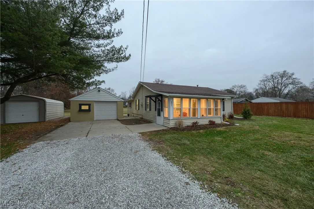 Bungalow featuring gravel driveway, a detached garage, and an outbuilding