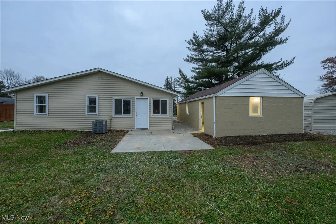 Rear view of property with a patio, a yard, and an outbuilding