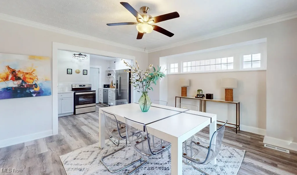 Dining area featuring crown molding, ceiling fan, and durable wood-look vinyl floors