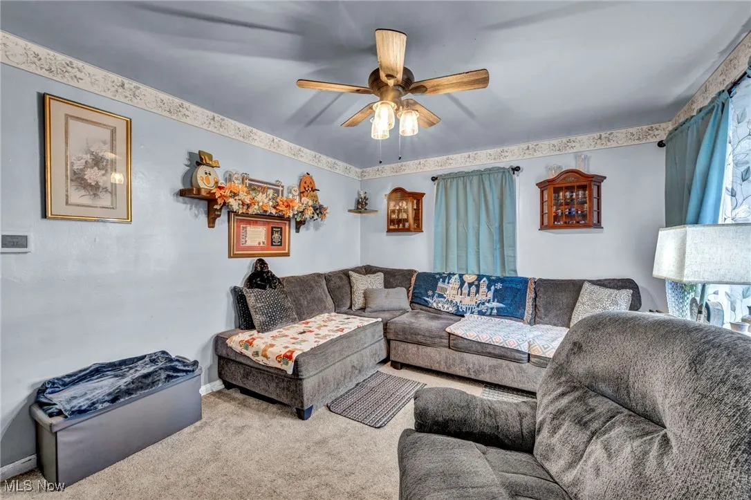 Carpeted living room with ceiling fan and baseboards