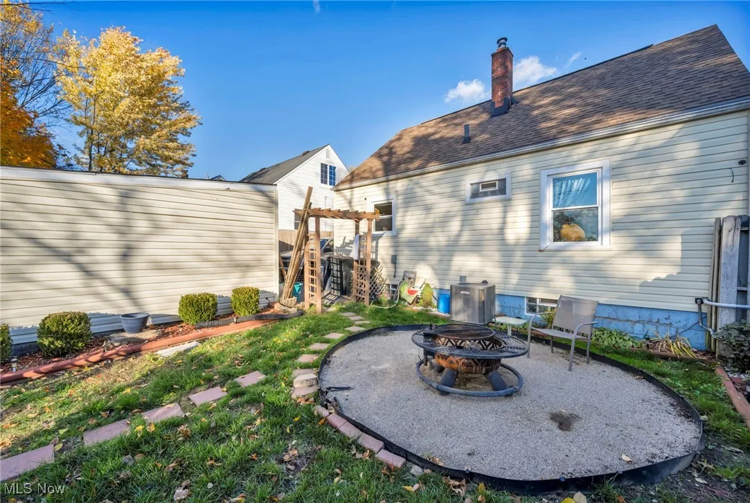Back of property with a patio area, an outdoor fire pit, a chimney, a shingled roof, and a pergola