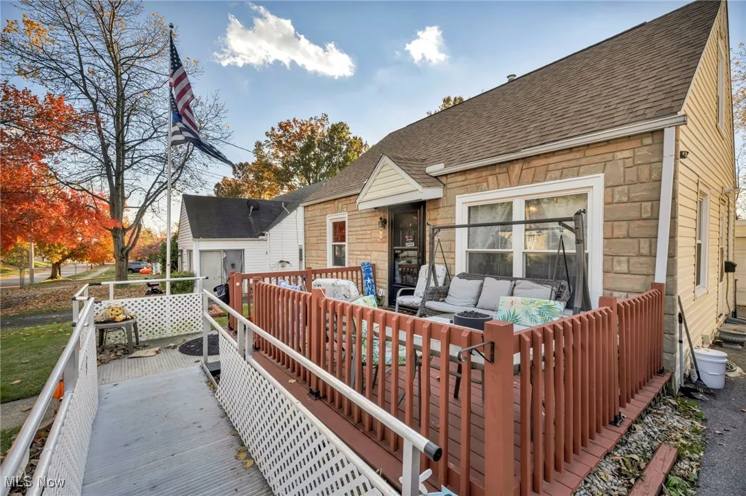 Rear view of property with stone siding, a shingled roof, an outdoor living space, and a wooden deck