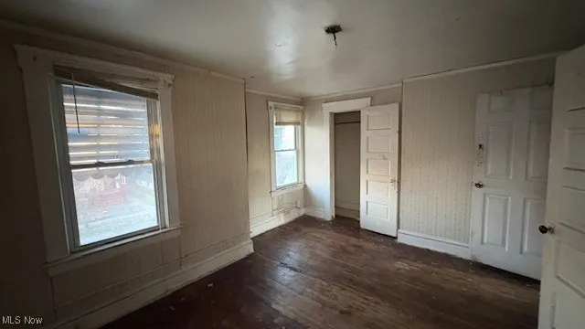 Unfurnished bedroom featuring a closet and dark wood-style floors